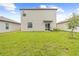 Expansive backyard with lush green grass, sliding glass doors, and partial shade provided by mature landscaping at 81 Rain Lily Ave, Spring Hill, FL 34609