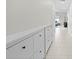 Hallway featuring white tile floors, white walls, and a long storage cabinet with black knobs at 81 Rain Lily Ave, Spring Hill, FL 34609