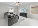 Comfortable living room with gray sectional sofa, modern TV stand, ceiling fan, and ample natural light at 81 Rain Lily Ave, Spring Hill, FL 34609