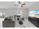 Cozy living room with a gray sectional, ceiling fan, modern TV stand, and natural light from the window at 81 Rain Lily Ave, Spring Hill, FL 34609