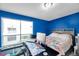 Bright bedroom features vibrant blue walls, a large window, and a cozy bed with a floral patterned comforter at 9481 Highland Oak Dr # 806, Tampa, FL 33647