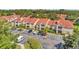 View of condominium building with red roof, balconies, palm trees, green bushes and a parking lot on a sunny day at 9481 Highland Oak Dr # 806, Tampa, FL 33647