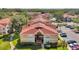 Exterior view of a well-maintained condominium building with a red roof, trimmed bushes, palms, and a parking lot at 9481 Highland Oak Dr # 806, Tampa, FL 33647