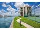 Coastal building featuring balconies, a waterfront walkway, tennis court, and lush landscaping at 1 Key Capri # 606W, Treasure Island, FL 33706
