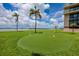 Green community putting green area with palm trees, a swing set, and waterfront views at 1 Key Capri # 606W, Treasure Island, FL 33706