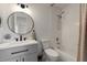 Bright bathroom featuring a round mirror, modern vanity, and tiled shower/tub combo at 10021 Brompton Dr, Tampa, FL 33626