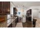 Galley kitchen with granite countertops, dark cabinets, stainless steel appliances, and view to eat-in area at 10021 Brompton Dr, Tampa, FL 33626