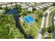 An aerial view of a well-maintained community tennis court surrounded by lush greenery and homes at 11144 Paradise Point Way, New Port Richey, FL 34654