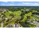 Aerial view showcasing a golf course with mature trees, ponds, and some residential housing in the background at 11144 Paradise Point Way, New Port Richey, FL 34654