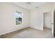Bright carpeted bedroom featuring a window with neighborhood views and adjacent hallway at 11144 Paradise Point Way, New Port Richey, FL 34654