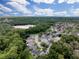 An aerial view shows a residential neighborhood nestled among green trees, near a lake under a bright cloudy sky at 12200 Hunters Lake Dr, New Port Richey, FL 34654