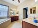 Spacious bathroom with a soaking tub, double vanity with wood cabinets, and tile flooring at 12200 Hunters Lake Dr, New Port Richey, FL 34654