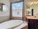 Elegant bathroom featuring a soaking tub with tiled surround and large window providing natural light at 12200 Hunters Lake Dr, New Port Richey, FL 34654