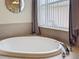 Bright bathroom highlighting an oval soaking tub with chrome fixtures and tiled platform at 12200 Hunters Lake Dr, New Port Richey, FL 34654
