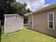 View of the backyard showcasing a shed next to the house and green lawn at 12200 Hunters Lake Dr, New Port Richey, FL 34654