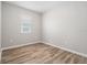 Bright, empty bedroom showcasing wood-style flooring and a large window with adjustable blinds at 12322 Eagle Swoop Pl, Riverview, FL 33579