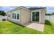 Exterior rear view showing a small patio, large windows, and a well-maintained lawn at 12322 Eagle Swoop Pl, Riverview, FL 33579
