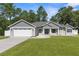 Charming single-story home with a manicured lawn, gray siding, and an attached two-car garage at 12333 Harris Hawk Rd, Weeki Wachee, FL 34614
