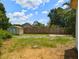 An overgrown backyard featuring a weathered shed, a wooden fence, and unkempt grass at 12704 Lacey, New Port Richey, FL 34654