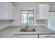Kitchen with white cabinets, granite countertops, and a stainless steel sink below a window at 1302 Twilridge Pl, Brandon, FL 33511