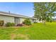 A single-story home featuring an expanse of lush grass, landscaping, and a sliding glass door at 1306 Idlewood Dr # 53, Sun City Center, FL 33573