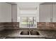 Modern kitchen featuring granite countertops and mosaic backsplash with a view to the outdoors at 1306 Idlewood Dr # 53, Sun City Center, FL 33573