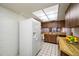 Spacious kitchen featuring white appliances, wooden cabinets, tile flooring, and a geometric patterned lighting panel at 2131 Ridge S Rd # 19, Largo, FL 33778