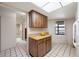 Kitchen area with wood cabinets, tile flooring, geometric patterned lighting panel, and a doorway to the hallway and bathroom at 2131 Ridge S Rd # 19, Largo, FL 33778