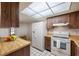 Bright kitchen features ample wood cabinetry, white appliances, tile floors, and a unique geometric patterned lighting panel at 2131 Ridge S Rd # 19, Largo, FL 33778