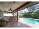 A cozy covered patio area with a ceiling fan, seating, and a view of the screened pool area at 2174 Kent Ave, Clearwater, FL 33764