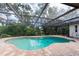 An inviting in-ground pool with a pool cleaner, set in a screened enclosure and a brick paver deck at 2174 Kent Ave, Clearwater, FL 33764