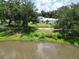 Scenic view of the home from across the pond, surrounded by mature trees and a well-maintained lawn at 21921 Us Highway 98, Dade City, FL 33523
