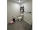 Cozy bathroom featuring gray tile floors, a toilet with toiletries on top, and a small black metal shelving unit at 2509 Thornbrook Pl, Tampa, FL 33618