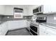 Modern kitchen featuring stainless steel appliances, white cabinetry, gray backsplash, and granite countertops at 3628 Holiday Lake Dr, Holiday, FL 34691