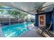 Covered outdoor pool area with fan, chairs and access to the house at 3628 Holiday Lake Dr, Holiday, FL 34691