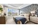 Bright bedroom with a patterned accent wall, tray ceiling, and large windows at 3840 Consolare Ct, Wesley Chapel, FL 33543
