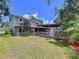 View of a backyard featuring a covered patio, grassy area, and mature trees for ample shade at 4030 Braesgate Ln, Tampa, FL 33624