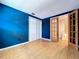 Bright bedroom features a vibrant blue accent wall, wood floors, and a closet with paneled sliding doors at 4030 Braesgate Ln, Tampa, FL 33624
