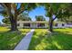 Attractive single-story home with well-kept lawn, mature trees, and stone walkway to the front door at 4391 Ne Cherry Ne St, St Petersburg, FL 33703
