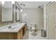 Well-lit bathroom featuring a double sink vanity, tiled walls, toilet, and door to the shower area at 525 Skylark Nw Ln, Port Charlotte, FL 33952