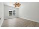 This is a bright bedroom that features modern, wood-style flooring, a ceiling fan, and a large window at 5390 Greystone Dr, Spring Hill, FL 34609
