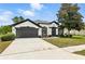Charming one-story home boasts a well-manicured lawn, two-car garage, and classic stucco exterior with black trim at 5390 Greystone Dr, Spring Hill, FL 34609