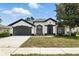 Charming one-story home boasts a well-manicured lawn, two-car garage, and classic stucco exterior with black trim at 5390 Greystone Dr, Spring Hill, FL 34609