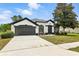 Charming one-story home boasts a well-manicured lawn, two-car garage, and classic stucco exterior with black trim at 5390 Greystone Dr, Spring Hill, FL 34609