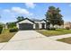 Charming one-story home boasts a well-manicured lawn, two-car garage, and classic stucco exterior with black trim at 5390 Greystone Dr, Spring Hill, FL 34609