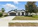 Charming one-story home boasts a well-manicured lawn, two-car garage, and classic stucco exterior with black trim at 5390 Greystone Dr, Spring Hill, FL 34609