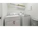 Bright laundry room features modern washer and dryer with storage shelves above at 5390 Greystone Dr, Spring Hill, FL 34609