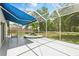 Relaxing screened patio with blue awning and tropical landscaping, perfect for enjoying the outdoors at 5390 Greystone Dr, Spring Hill, FL 34609