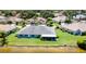 Aerial view of a single-story home showcasing a screened lanai, well-kept lawn, and serene water views at 717 Manchester Woods Dr # 717, Sun City Center, FL 33573