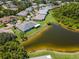 An aerial shot features a tranquil pond adjacent to a property nestled amid lush landscaping and mature trees at 717 Manchester Woods Dr # 717, Sun City Center, FL 33573